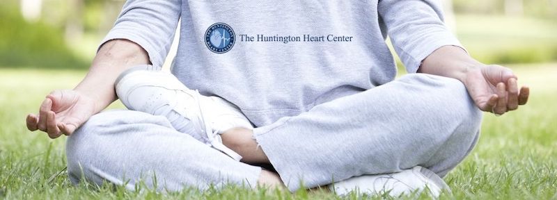 Woman sits in grass practicing meditation for her heart health as recommended by Huntington Heart Center