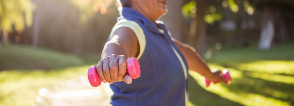 Woman exercises in park using light weights for added resistance after a recent heart attack with recommendations for her cardiologist at Huntington Heart Center 