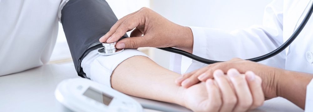 Doctor measuring the blood pressure of a patient using a cuff and a stethoscope